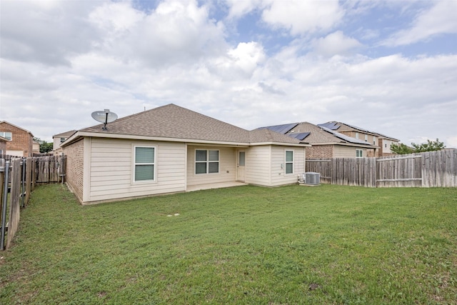 back of house featuring a lawn, roof with shingles, a fenced backyard, and central AC