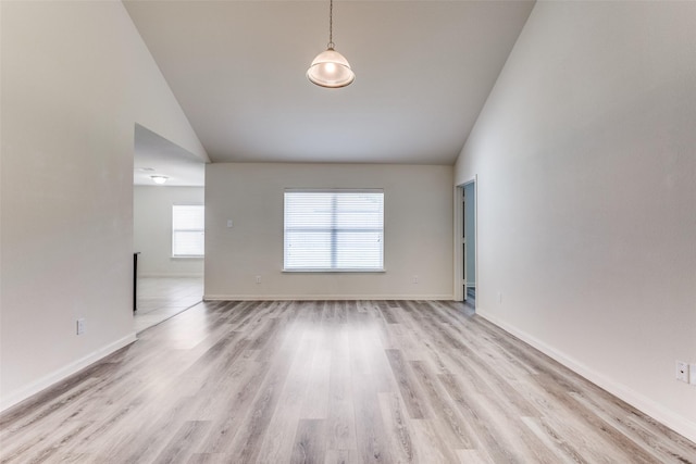 spare room with baseboards, high vaulted ceiling, and light wood-style flooring