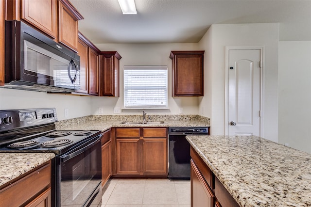 kitchen with a sink, light tile patterned floors, light stone countertops, and black appliances
