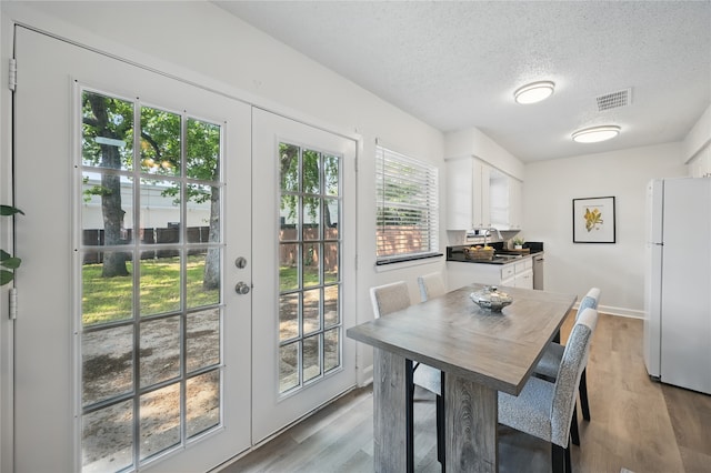 528 Chambers St, Denton, TX 76205 - dining space with visible vents, a textured ceiling, wood finished floors, and french doors
