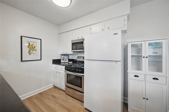 528 Chambers St, Denton, TX 76205 - kitchen featuring a textured ceiling, light wood-type flooring, baseboards, stainless steel appliances, and white cabinetry