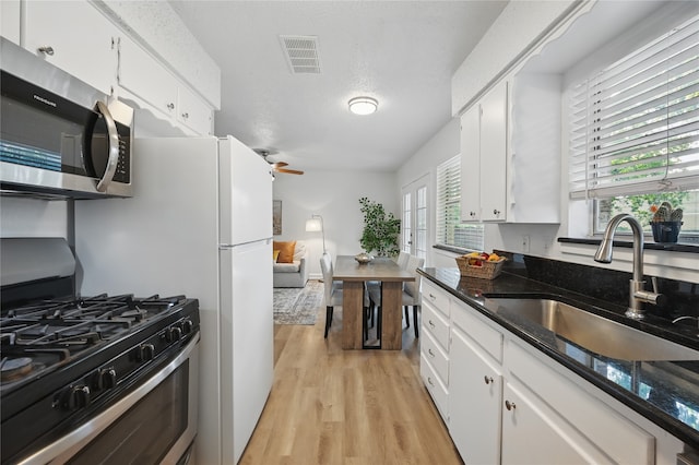 528 Chambers St, Denton, TX 76205 - kitchen featuring visible vents, light wood finished floors, appliances with stainless steel finishes, and white cabinetry