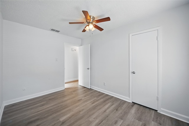 528 Chambers St, Denton, TX 76205 - unfurnished bedroom featuring ceiling fan, a textured ceiling, visible vents, wood finished floors, and baseboards
