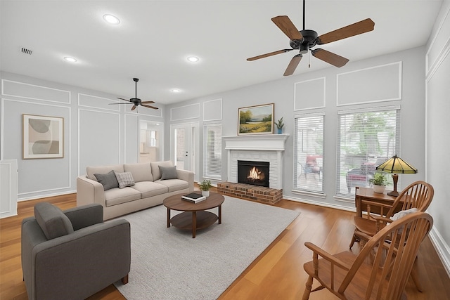 818 Red Oak Dr, Mansfield, TX 76063 - living room with ceiling fan, a decorative wall, wood finished floors, a brick fireplace, and recessed lighting