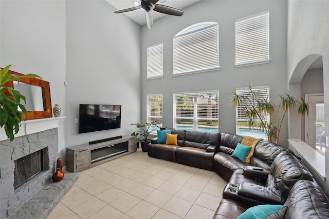 8208 Rock Elm Rd, Fort Worth, TX 76131 - living room featuring a towering ceiling, light tile patterned floors, ceiling fan, a fireplace, and arched walkways