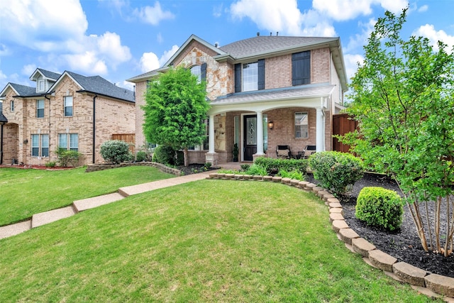 traditional-style home featuring fence, a front yard, a porch, and brick siding