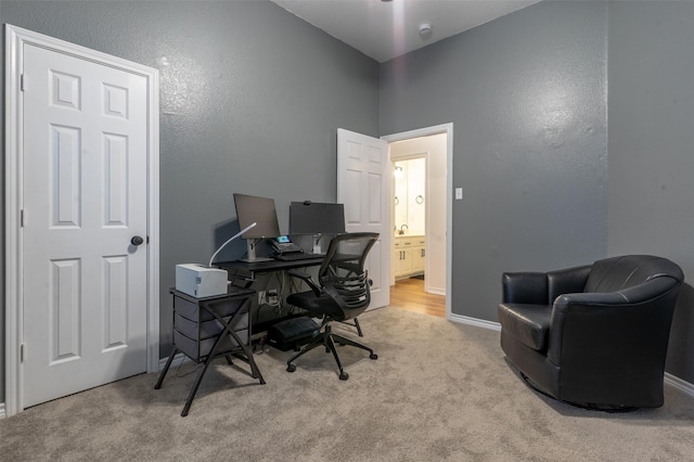 office area featuring baseboards, a textured wall, and carpet