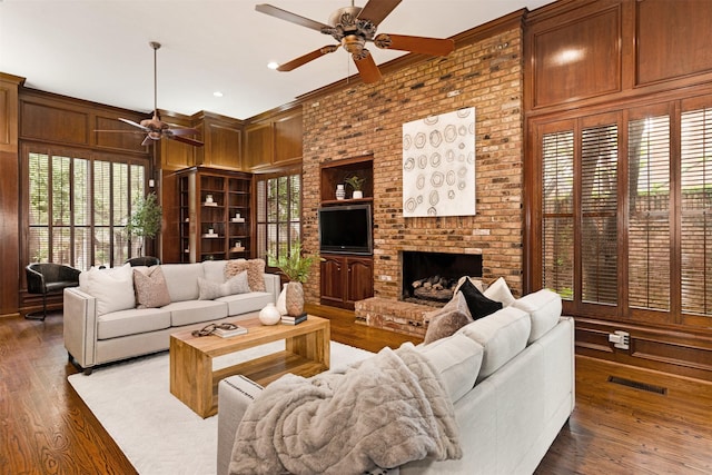 living area with wood finished floors, ceiling fan, a wealth of natural light, and a fireplace