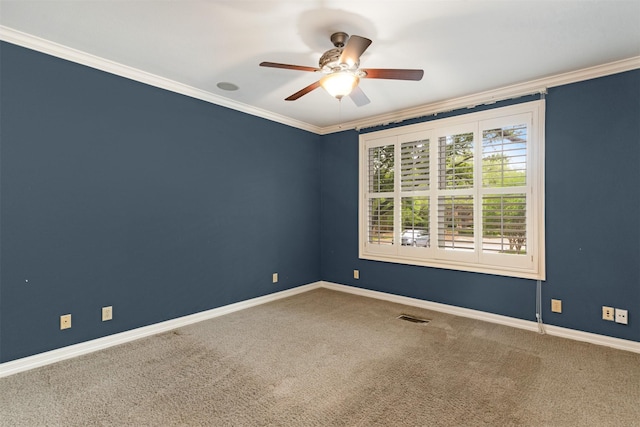 empty room with a ceiling fan, visible vents, crown molding, baseboards, and carpet flooring