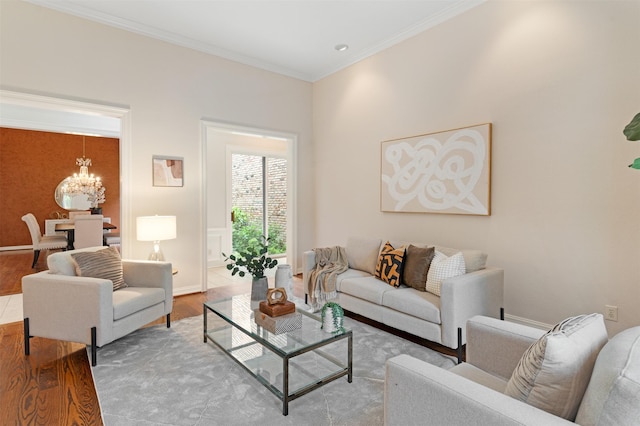 living area featuring baseboards, a notable chandelier, ornamental molding, and wood finished floors