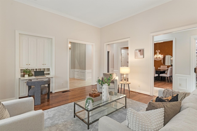 living area with an inviting chandelier, ornamental molding, wood finished floors, and visible vents
