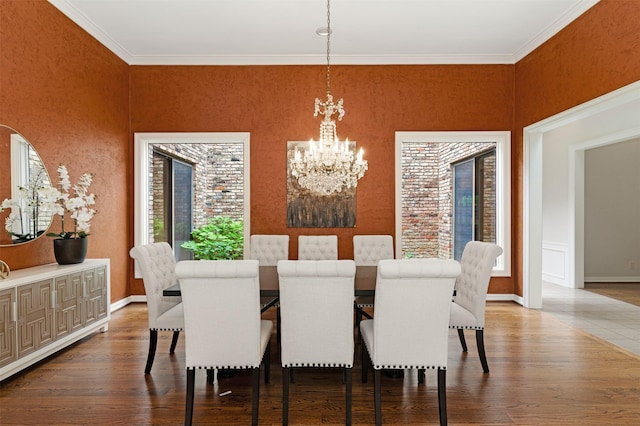 dining space featuring crown molding, baseboards, wood finished floors, and a notable chandelier