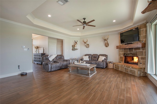living room featuring visible vents, wood finished floors, a fireplace, a raised ceiling, and a ceiling fan