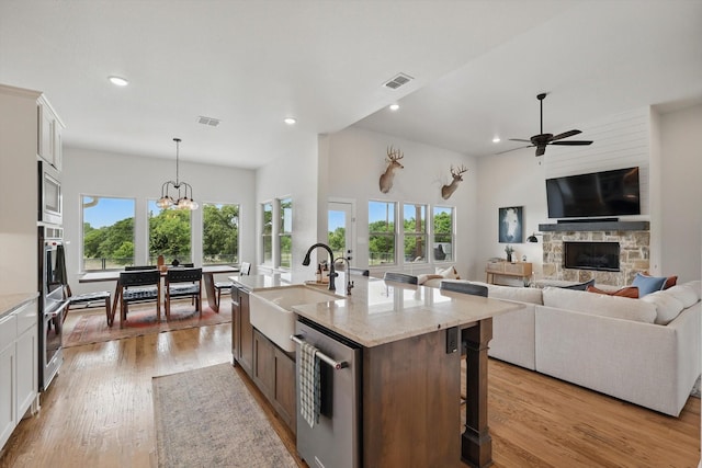 kitchen featuring visible vents, a sink, ceiling fan with notable chandelier, and a healthy amount of sunlight