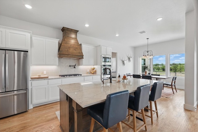 kitchen with backsplash, visible vents, appliances with stainless steel finishes, custom range hood, and white cabinetry