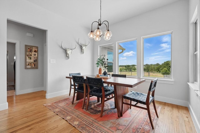 dining room with baseboards, an inviting chandelier, and light wood-style floors