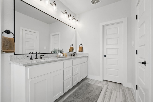 full bath with double vanity, baseboards, a sink, and visible vents