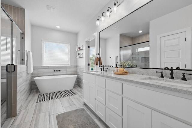 bathroom featuring a sink, tile walls, a stall shower, and double vanity