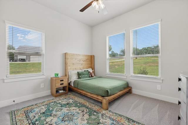 carpeted bedroom featuring baseboards, multiple windows, and ceiling fan