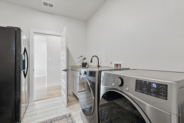 laundry area with baseboards, visible vents, cabinet space, and washing machine and clothes dryer