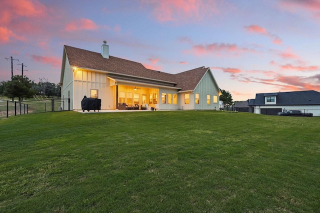 rear view of house featuring a lawn, board and batten siding, and a chimney