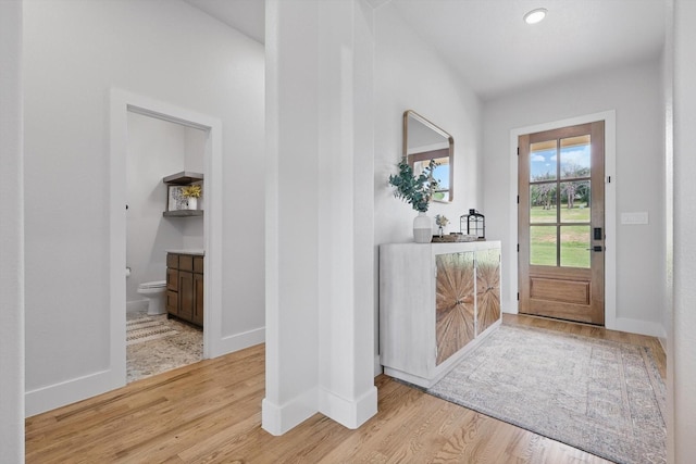 doorway to outside featuring baseboards and wood finished floors