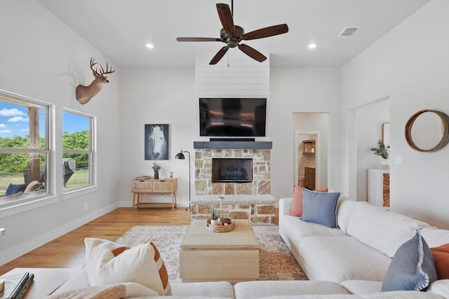 living area with a ceiling fan, visible vents, a fireplace, wood finished floors, and recessed lighting