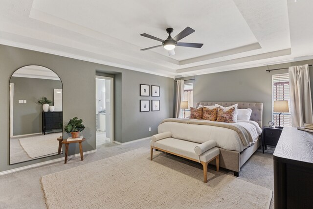 bedroom featuring arched walkways, multiple windows, light carpet, and a tray ceiling