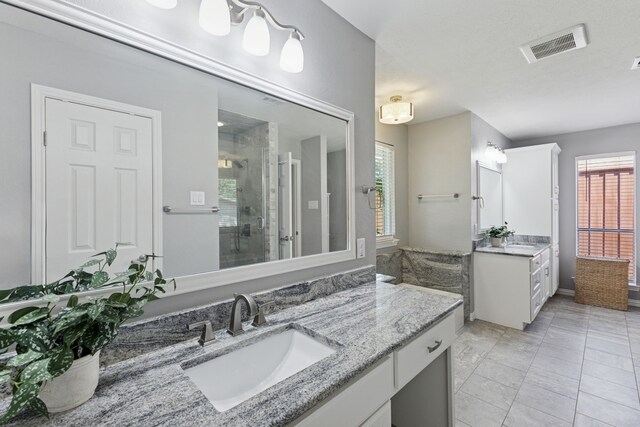 bathroom with visible vents, a sink, a stall shower, and two vanities