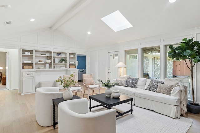 living room featuring visible vents, light wood-style flooring, a decorative wall, and vaulted ceiling with skylight