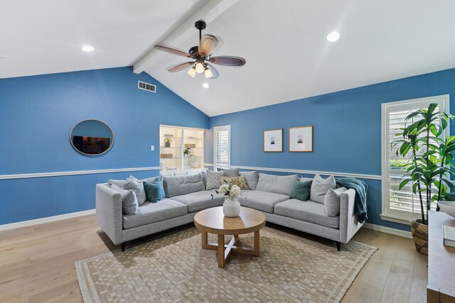 living area featuring a ceiling fan, visible vents, a wealth of natural light, and vaulted ceiling with beams