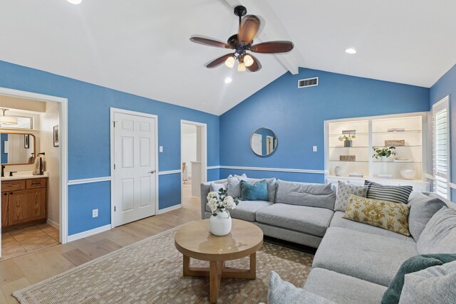 living area with ceiling fan, visible vents, baseboards, light wood-style floors, and vaulted ceiling with beams