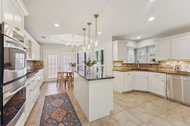 kitchen with white cabinets, a sink, stainless steel appliances, light tile patterned floors, and backsplash