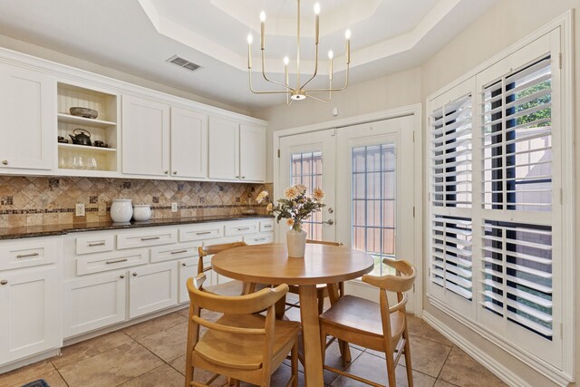 dining area featuring visible vents, light tile patterned flooring, a chandelier, and a tray ceiling
