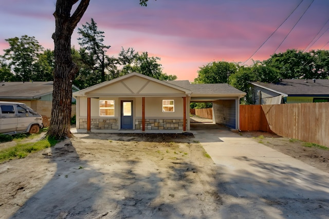 2188 Jordan Valley Dr, Dallas, TX 75253 - view of front facade with concrete driveway, fence, covered porch, stone siding, and an attached carport