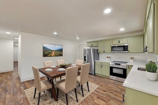 2188 Jordan Valley Dr, Dallas, TX 75253 - kitchen with green cabinets, stainless steel appliances, a sink, light countertops, and light wood-style floors