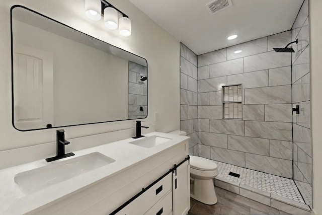 2188 Jordan Valley Dr, Dallas, TX 75253 - bathroom featuring tiled shower, toilet, wood finished floors, double vanity, and recessed lighting