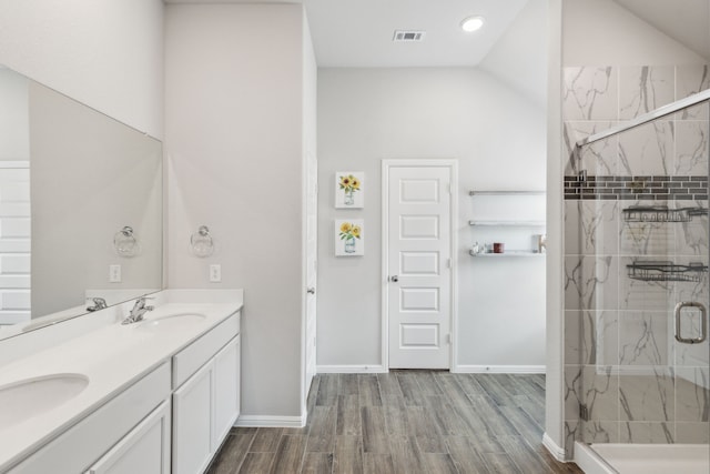 full bathroom featuring a sink, double vanity, a marble finish shower, wood finished floors, and visible vents