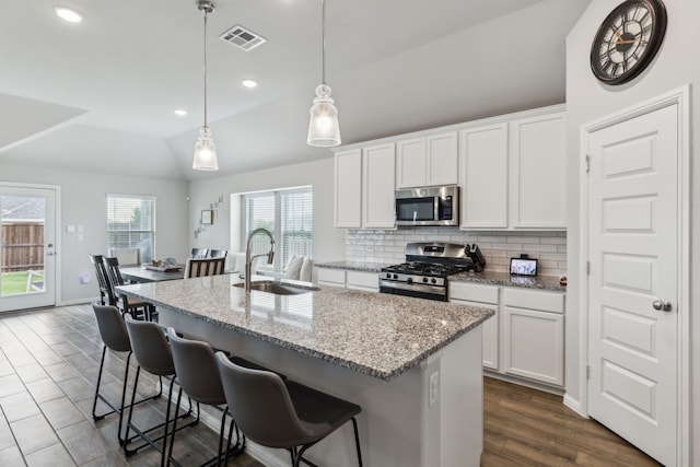 kitchen with decorative backsplash, visible vents, appliances with stainless steel finishes, a sink, and lofted ceiling