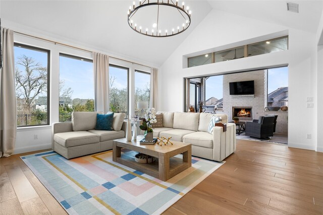 living area with light wood-style floors, high vaulted ceiling, a fireplace, and visible vents