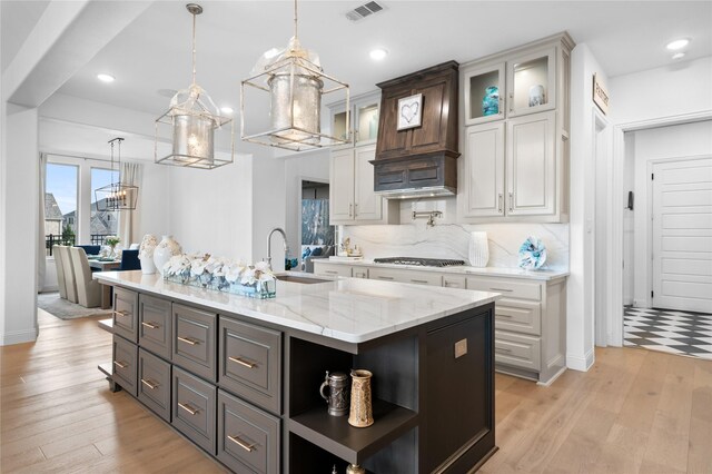 kitchen featuring gas cooktop, visible vents, a sink, an inviting chandelier, and white cabinetry