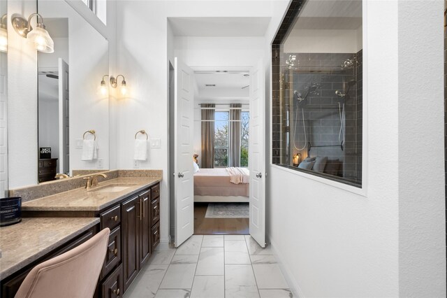 ensuite bathroom featuring a tile shower, ensuite bathroom, marble finish floor, and vanity