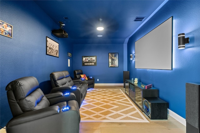 home theater room featuring baseboards, visible vents, and wood finished floors