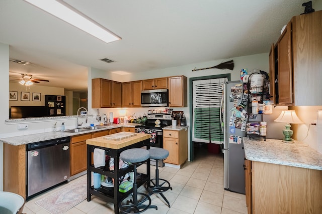 kitchen featuring visible vents, a ceiling fan, a sink, light tile patterned floors, and stainless steel appliances