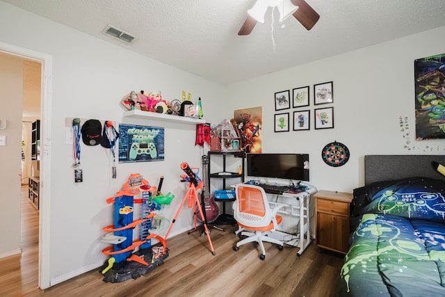 bedroom featuring baseboards, ceiling fan, wood finished floors, and visible vents