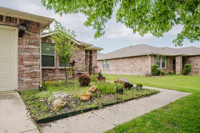 view of front of house with fence, a shingled roof, brick siding, and a front yard