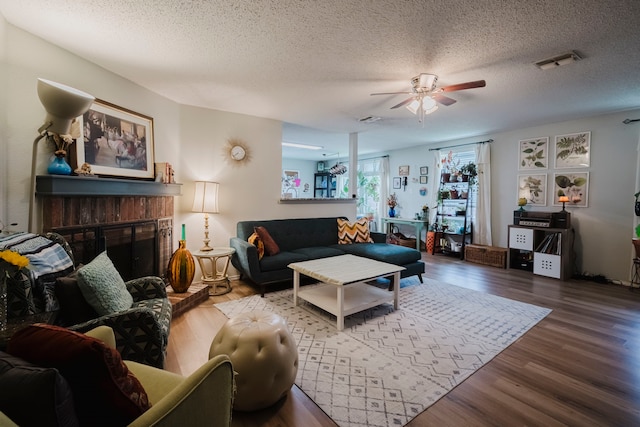 living room featuring a textured ceiling, ceiling fan, wood finished floors, and visible vents