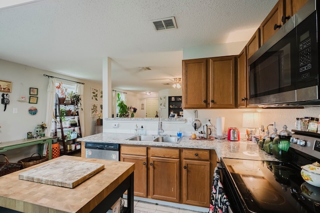 kitchen featuring brown cabinets, appliances with stainless steel finishes, a sink, visible vents, and butcher block counters