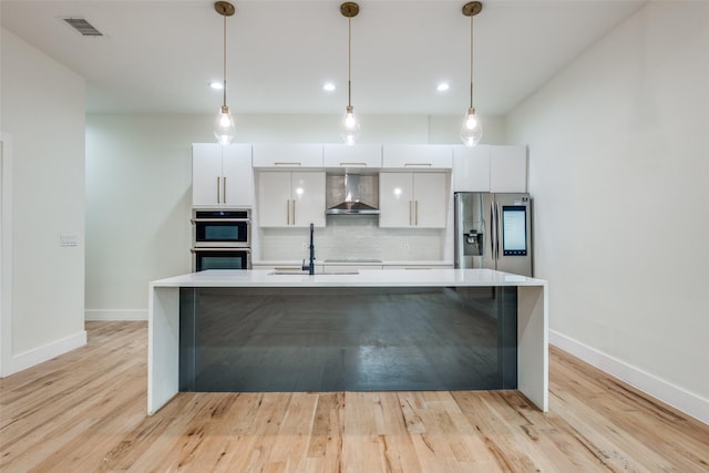 kitchen with wall chimney range hood, visible vents, appliances with stainless steel finishes, modern cabinets, and white cabinets