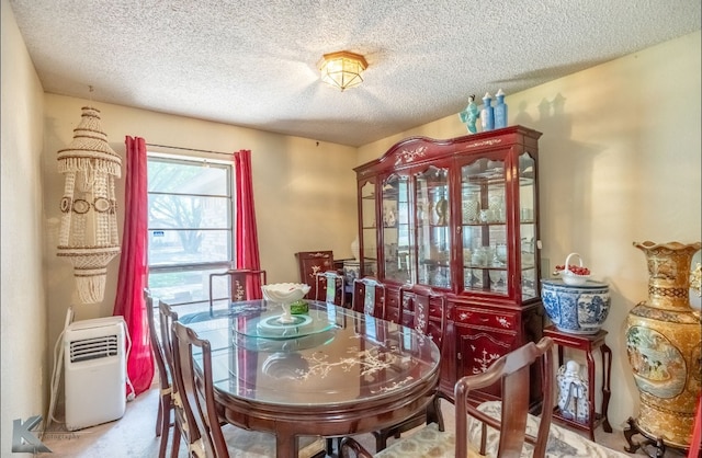 carpeted dining room with a textured ceiling